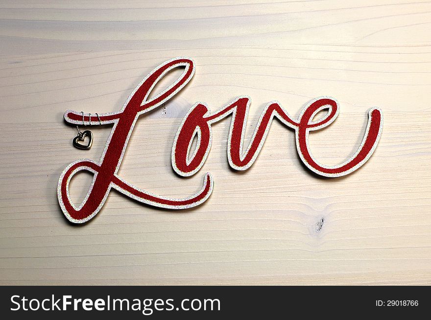 The word, Love, spelled in red script letters on white shabby chic table. The word, Love, spelled in red script letters on white shabby chic table