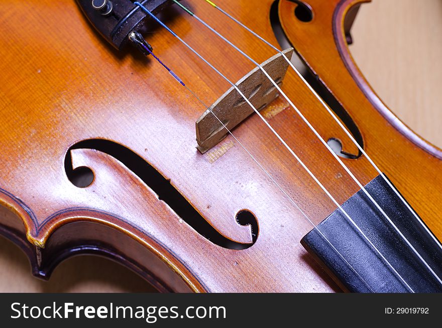 Single soft brown violin with brown wallpaper