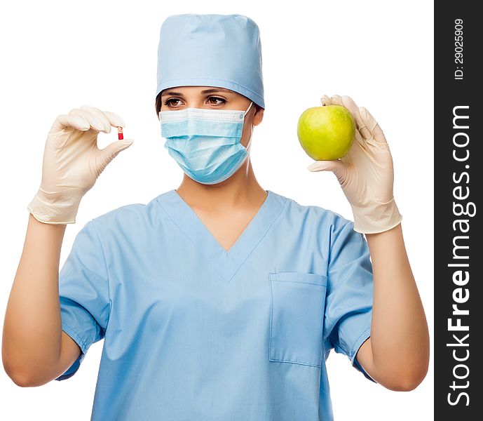 Young doctor holding pill and apple, looking at pill. isolated white background