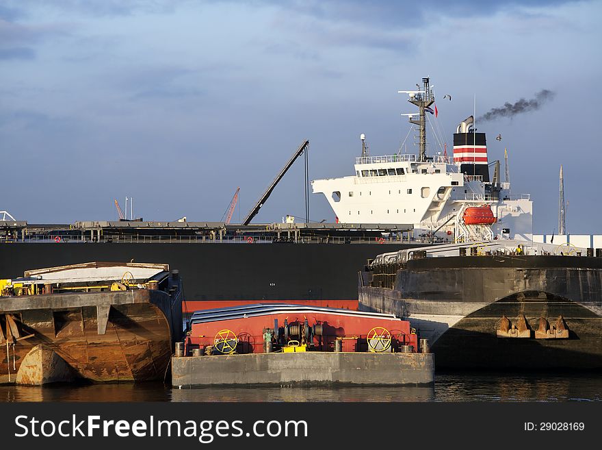 Push barges moored in the port and a bulk carrier in the background in the Port of Rotterdam. Push barges moored in the port and a bulk carrier in the background in the Port of Rotterdam