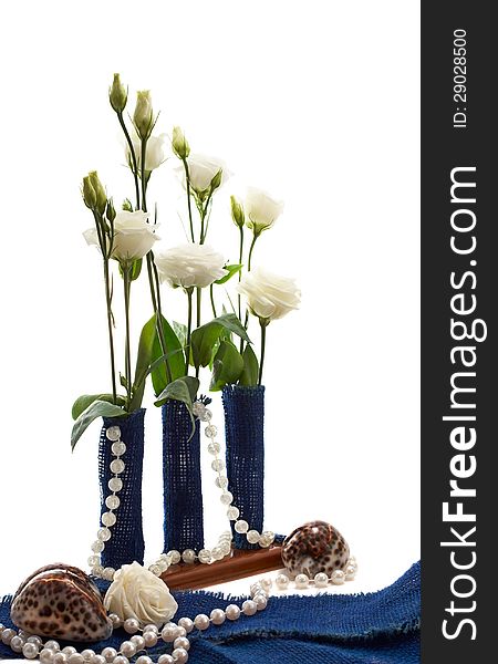 Eustoma flowers in a composition with blue sackcloth tubes, shells and pearl bead isolated on a white. Eustoma flowers in a composition with blue sackcloth tubes, shells and pearl bead isolated on a white
