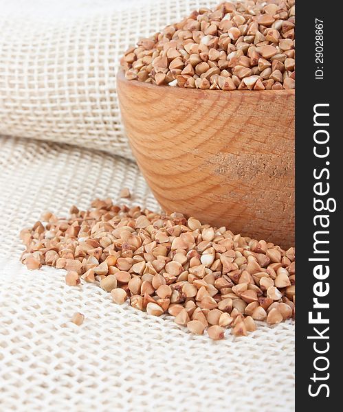 Raw buckwheat in wooden bowl and spoon on burlap, food ingredient photo