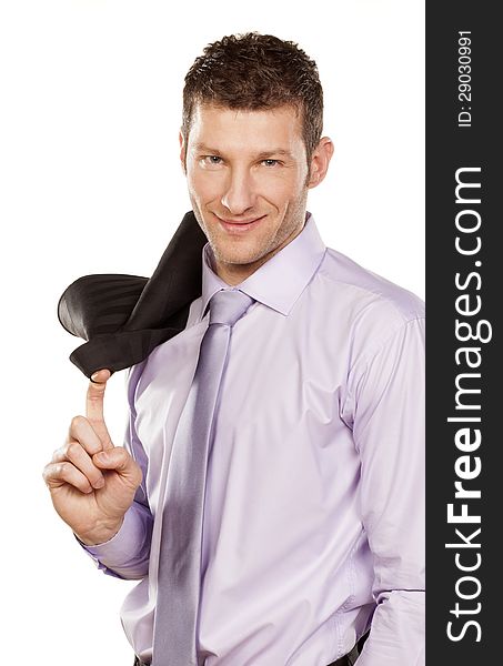 Smiling handsome businessman in a shirt with a jacket over his shoulder standing on white background