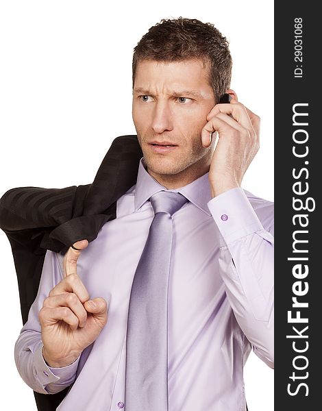 Serious businessman with a jacket over his shoulder telephones on white background