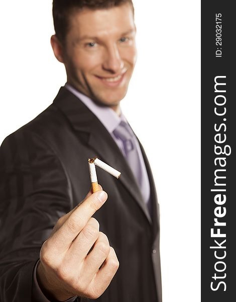 Smiling handsome businessman holding a broken cigarette in his hand on white background. Smiling handsome businessman holding a broken cigarette in his hand on white background