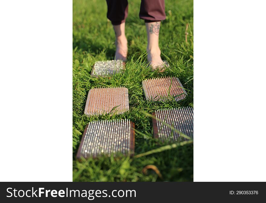 Standing On Nails. Nature. Meditation. The Girl Steps On The Boards With Sharp Zinc And Copper Nails.