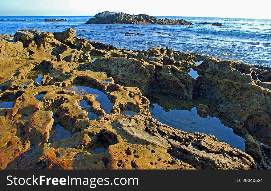 Interesting geologic rock formation in foreground with tide pools and  Bird Rock in background near the Main Beach of Laguna Beach, California. Interesting geologic rock formation in foreground with tide pools and  Bird Rock in background near the Main Beach of Laguna Beach, California.