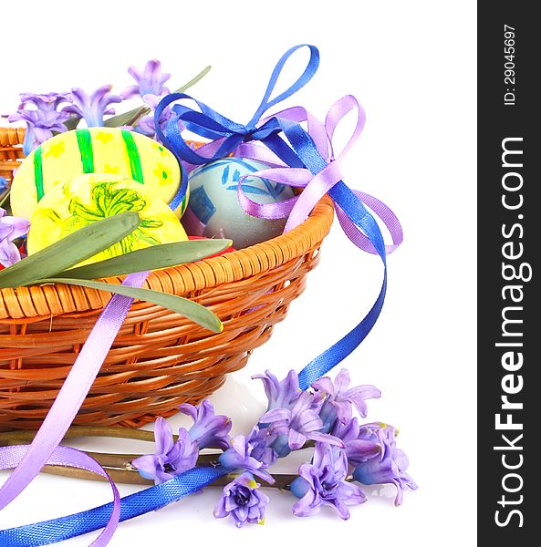 Colorful painted Easter eggs with violet flowers and ribbons in wooden basket. Colorful painted Easter eggs with violet flowers and ribbons in wooden basket