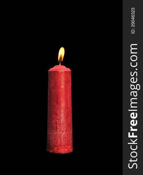 A single burning red candle isolated in front of black background