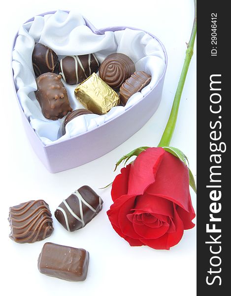 Assortment of chocolates inside a heartshaped box with a card and decorative red ribbon. Assortment of chocolates inside a heartshaped box with a card and decorative red ribbon