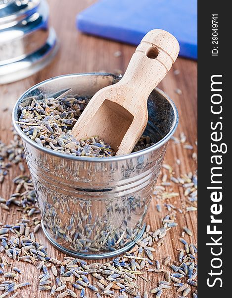 Pail of dry lavender and wooden scoop on a dark wooden background