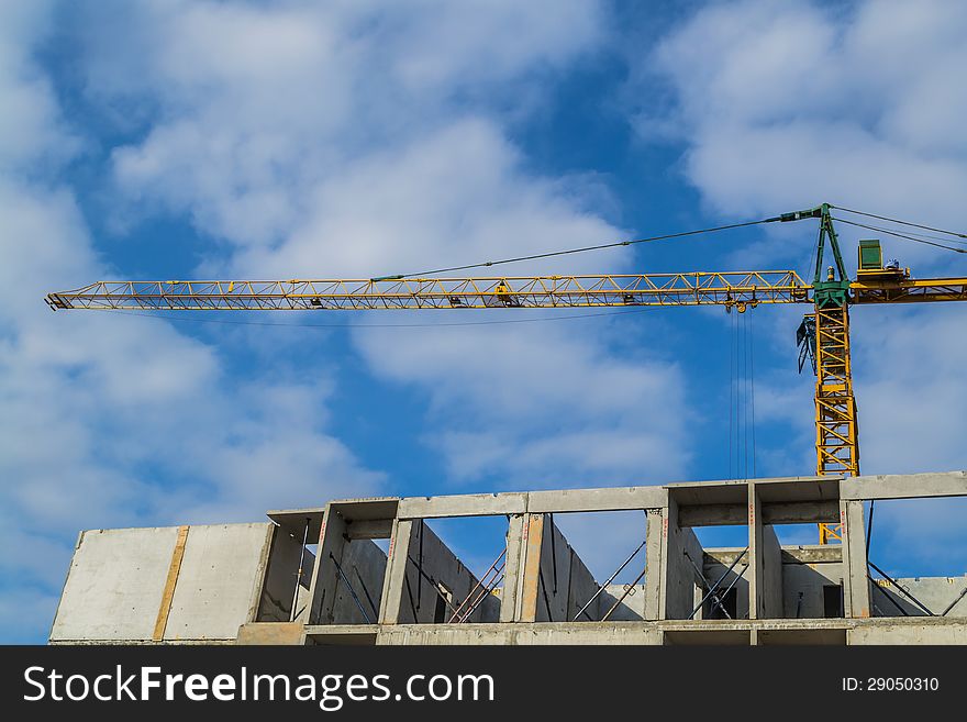 Crane and construction site with cloudy blue sky