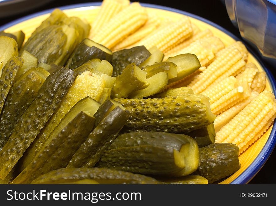 Image of pickles and corn on the plate.