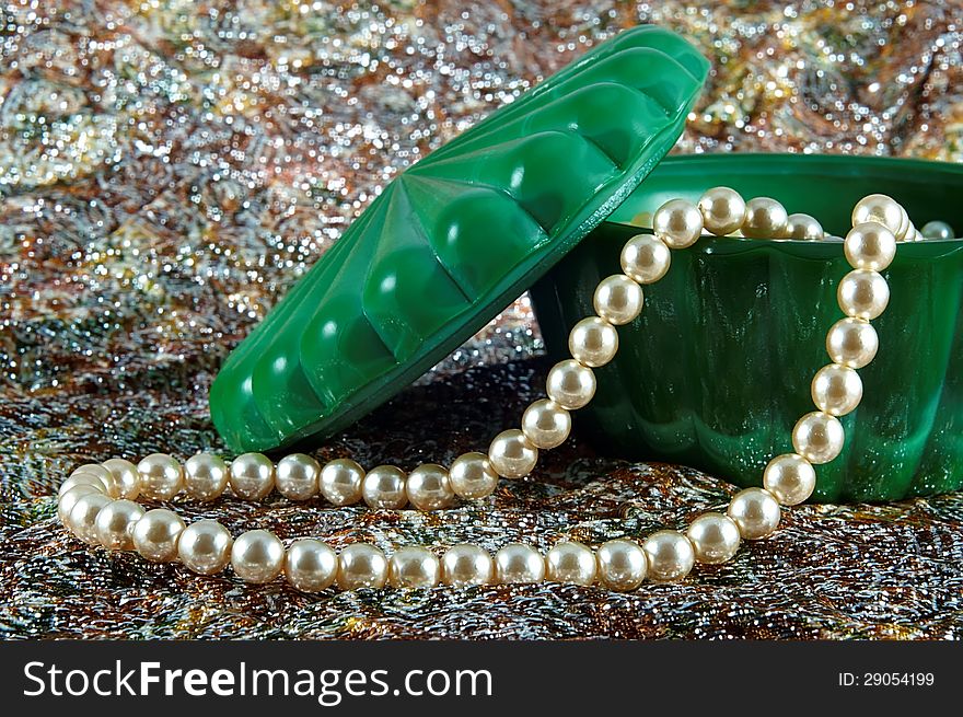 Pearl necklace spanning the green porcelain bowl with cap