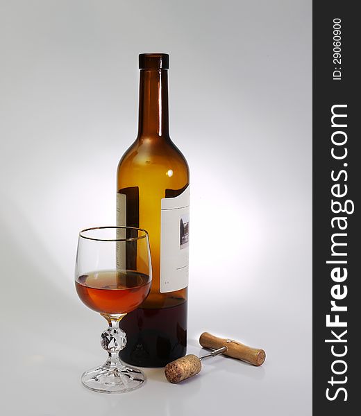 A glass of wine, a bottle, and corkscrew on a gray background