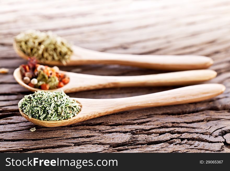 Variety of spices in the spoons on an old wooden table. Variety of spices in the spoons on an old wooden table.