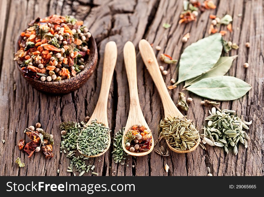 Variety of spices in the spoons on an old wooden table. Variety of spices in the spoons on an old wooden table.