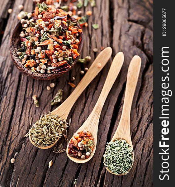 Variety of spices in the spoons on an old wooden table. Variety of spices in the spoons on an old wooden table.