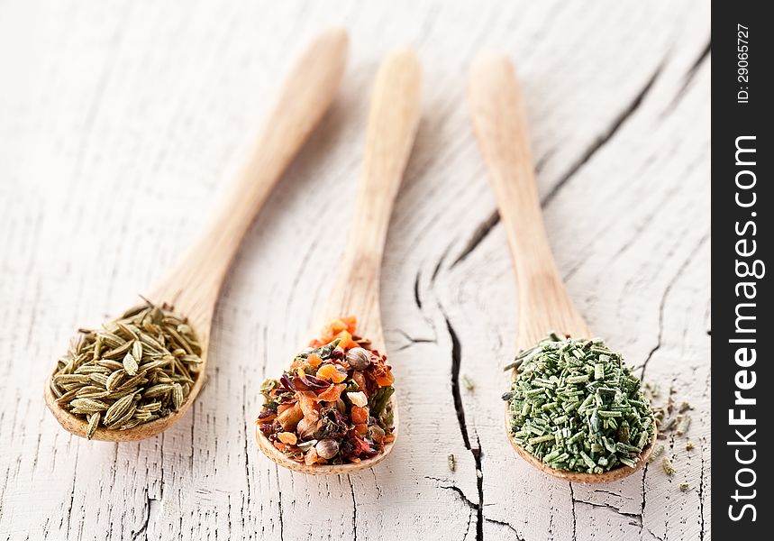 Variety of spices in the spoons on an white old wooden table. Variety of spices in the spoons on an white old wooden table.