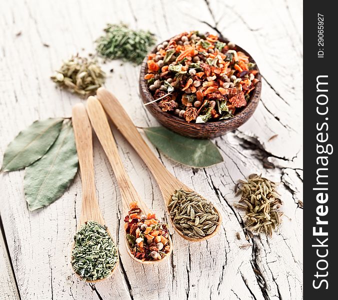 Variety of spices in the spoons on an white old wooden table. Variety of spices in the spoons on an white old wooden table.