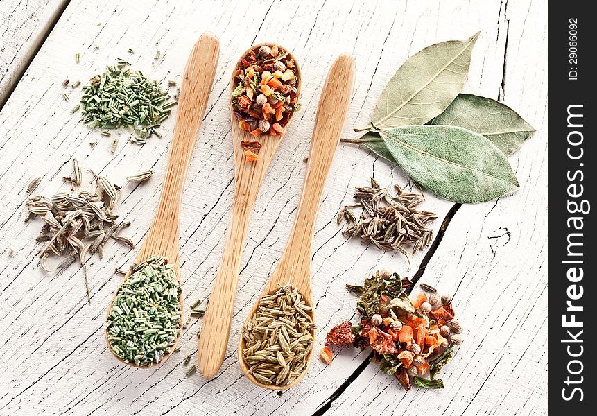 Variety of spices in the spoons on an white old wooden table. Variety of spices in the spoons on an white old wooden table.