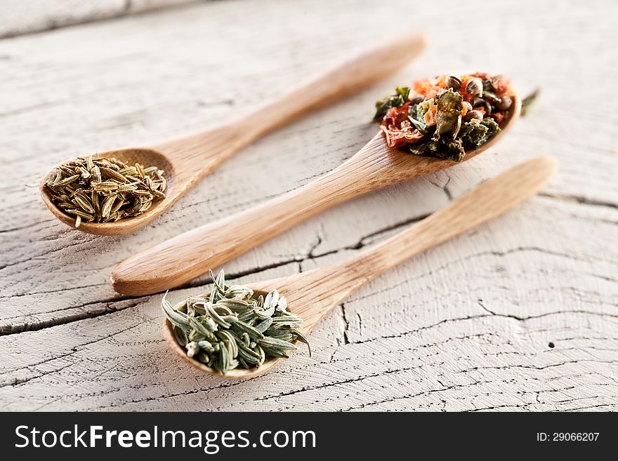 Variety of spices in the spoons on an white old wooden table. Variety of spices in the spoons on an white old wooden table.