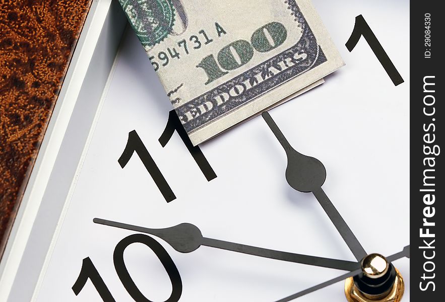 Time is money. hour hand points to the U.S. hundred dollar bill.