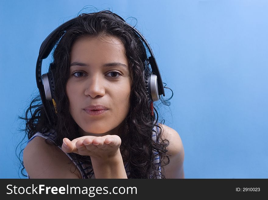 Young beautiful girl listening music on blue background