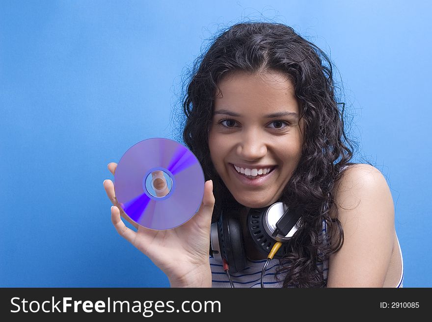 Young beautiful girl listening music on blue background