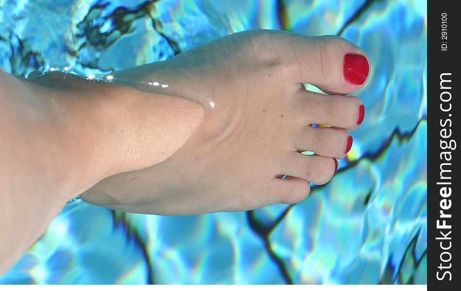 Woman foot with red nails in the swimming pool. Woman foot with red nails in the swimming pool