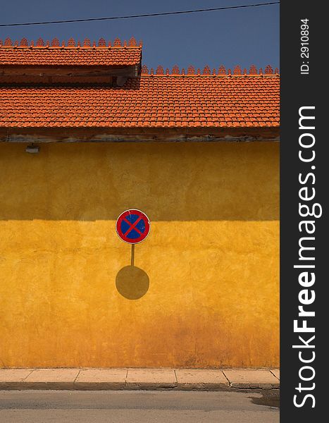 A no parking sign on an orange wall in the south of europe