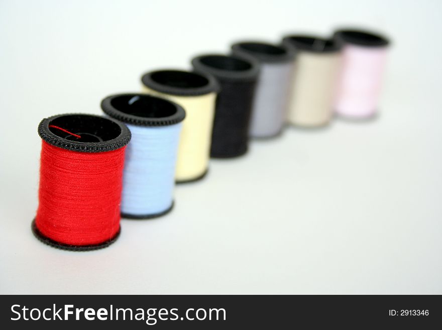 Line of   of multi colored thread spools. Line of   of multi colored thread spools