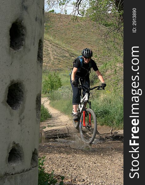 A woman mountain biker in the hills spashes through a puddle. A woman mountain biker in the hills spashes through a puddle