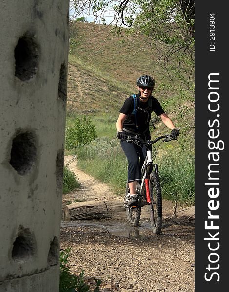 A woman mountain biker in the hills spashes through a puddle. A woman mountain biker in the hills spashes through a puddle