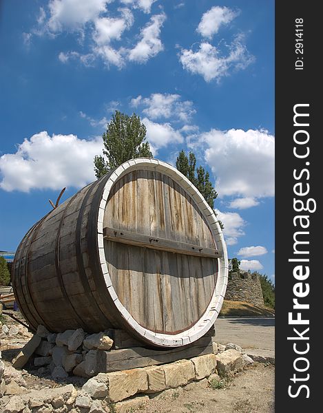 Big single wine barrel placed on bricks on sky background