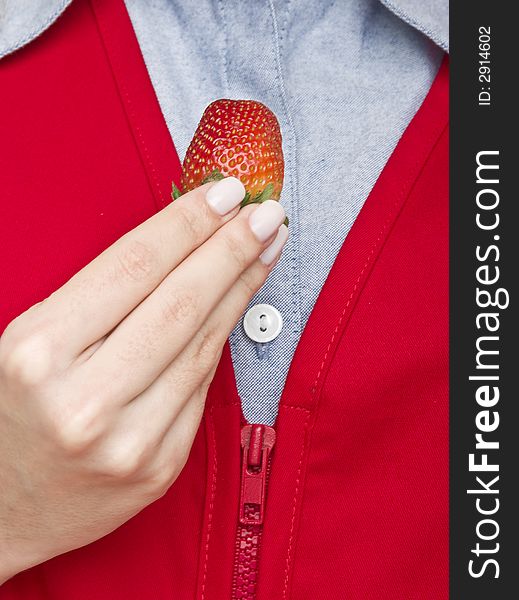 A fresh strawberry held by a female hand