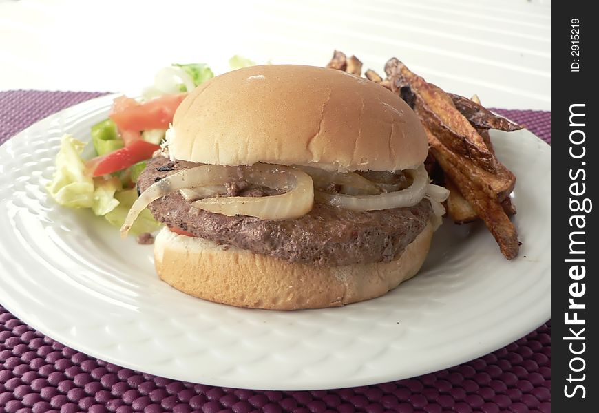 Photo of a burger sandwich with salad and sausage on the side. Photo of a burger sandwich with salad and sausage on the side