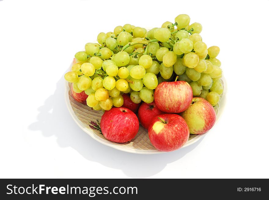 Grapes and apples  on plate on white background