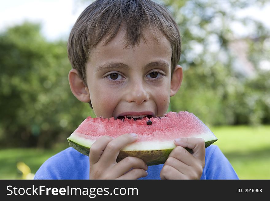 Boy eats watermelon in courtyard