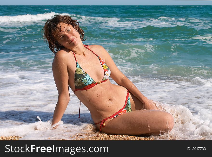 Woman sitting in the waves on sand beach. Woman sitting in the waves on sand beach