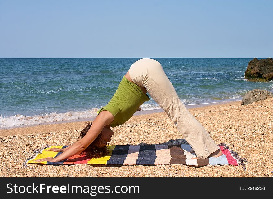 Girl doing Adho Mukha Svanasana yoga pose on sea beach. Girl doing Adho Mukha Svanasana yoga pose on sea beach
