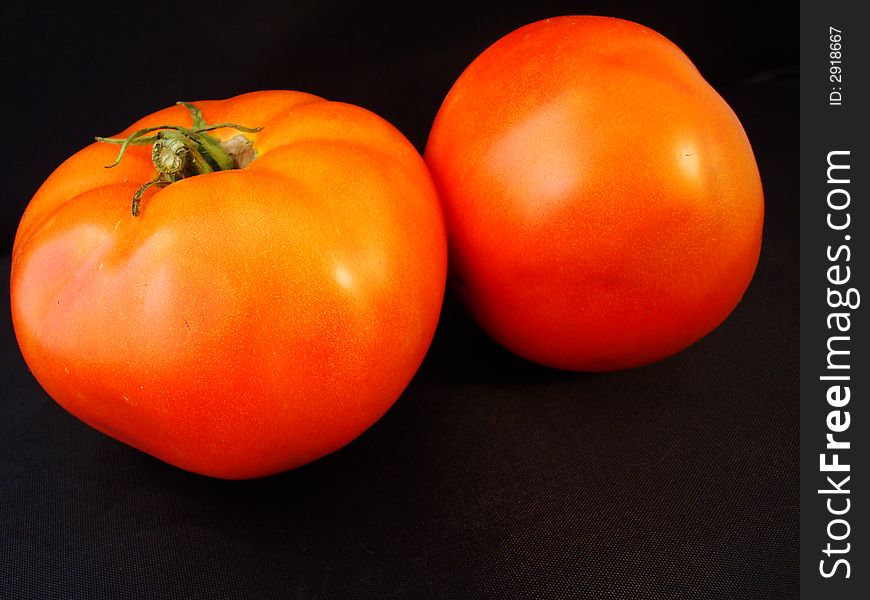 Two imperfect tomatoes fresh from the garden set on a black background. Two imperfect tomatoes fresh from the garden set on a black background.