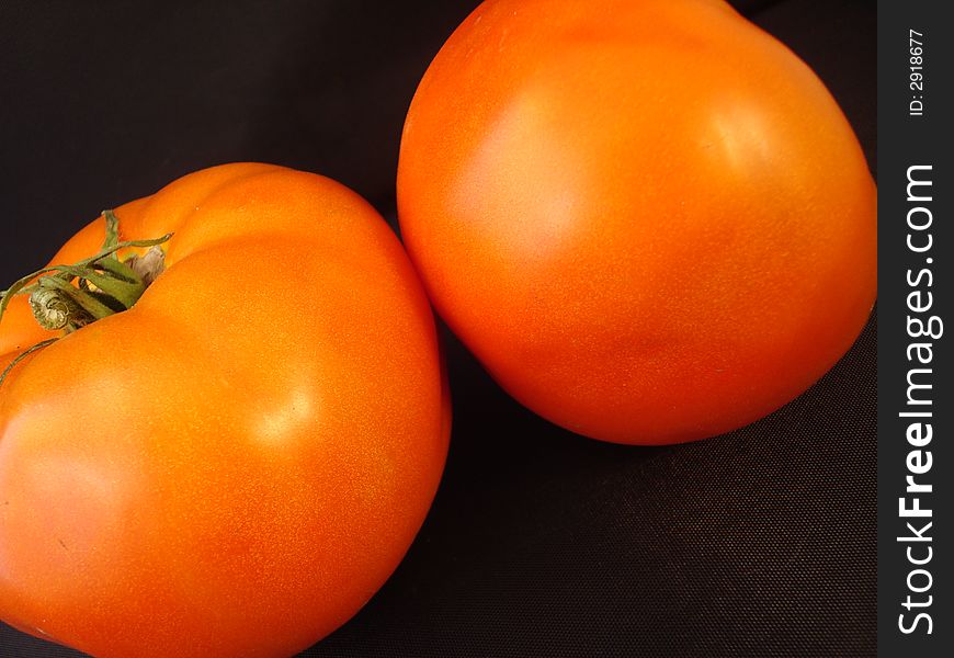 Two imperfect tomatoes fresh from the garden set on a black background. Two imperfect tomatoes fresh from the garden set on a black background.