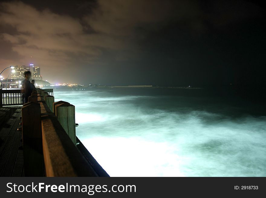 Fisherman on pier by night