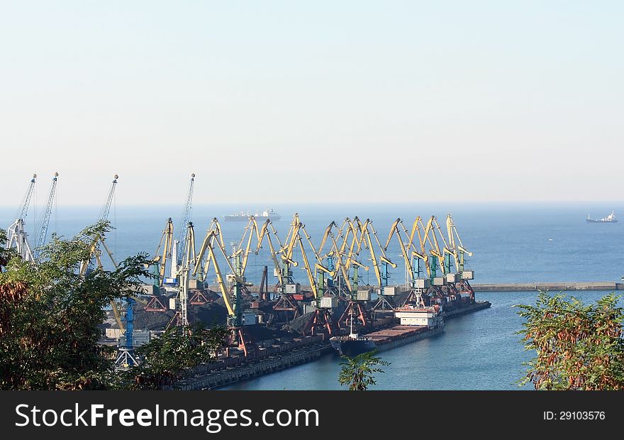 Port berth with material handling equipment and cargo ships at anchor. Port berth with material handling equipment and cargo ships at anchor