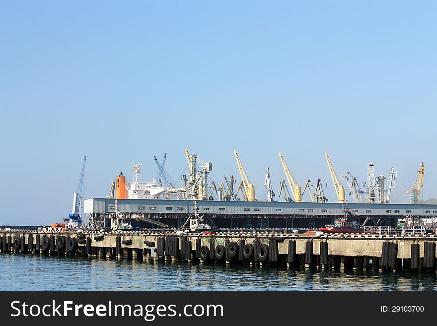 Port berth with material handling equipment and cargo ships at anchor. Port berth with material handling equipment and cargo ships at anchor