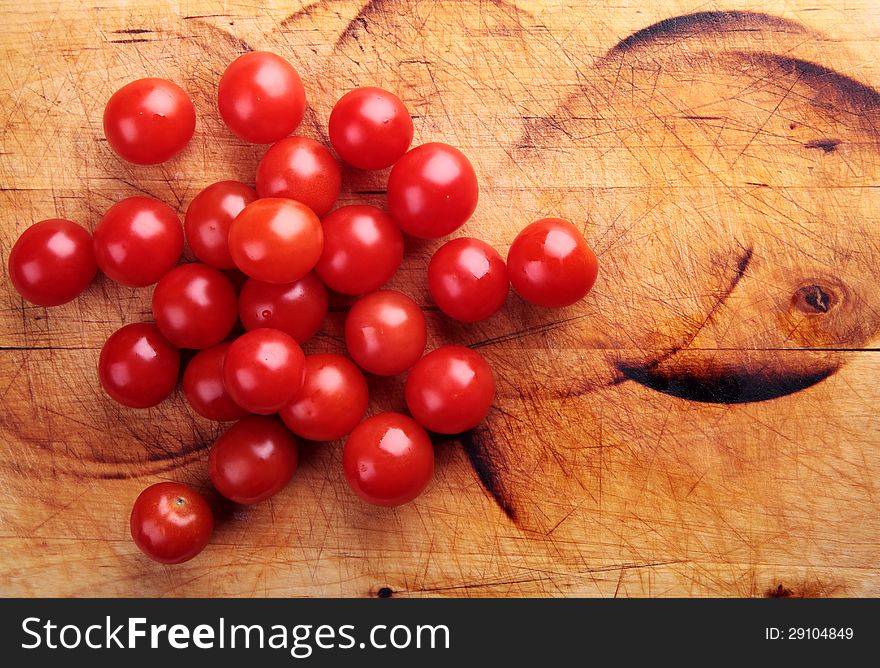 Red cherry tomatoes on a wooden board.