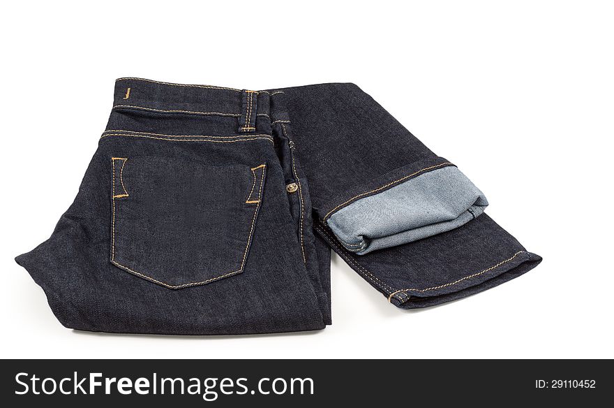 A pair of neatly displayed denim jeans showing the pocket stitching and with the leg folded out sideways and turned up to show the inside of the fabric on white