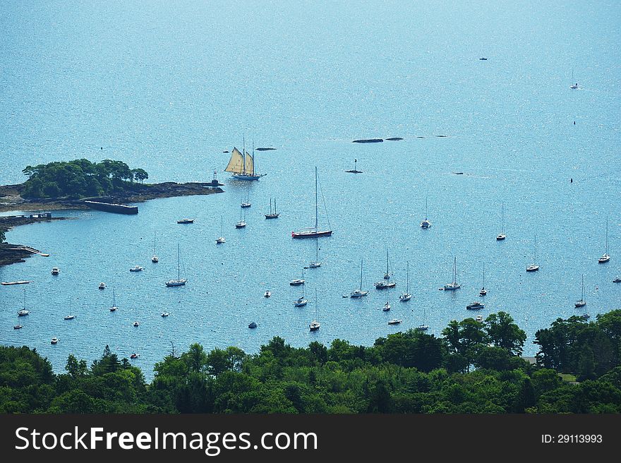 Multi-sailed clipper ship coming into the safety of a harbor as seen from a mountain top. Multi-sailed clipper ship coming into the safety of a harbor as seen from a mountain top