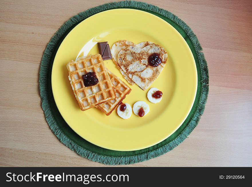 Heart-shaped pancakes and waffle with banana and raspberry jam. A perfect breakfast for Valentine's Day.